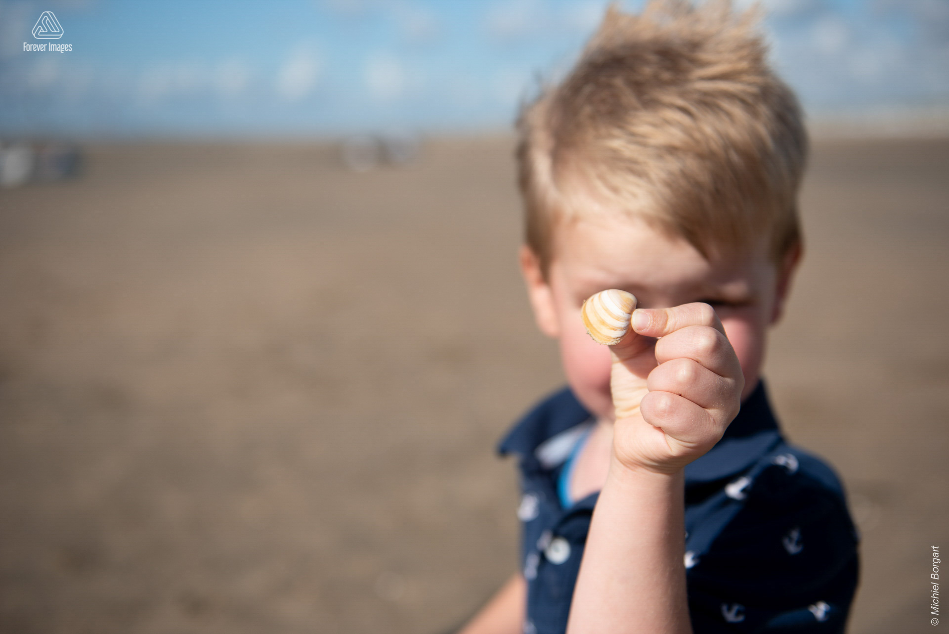 Kinderfoto strand verschuilen achter een schelp | Elias IJmuiden Strand | Portretfotograaf Michiel Borgart - Forever Images.