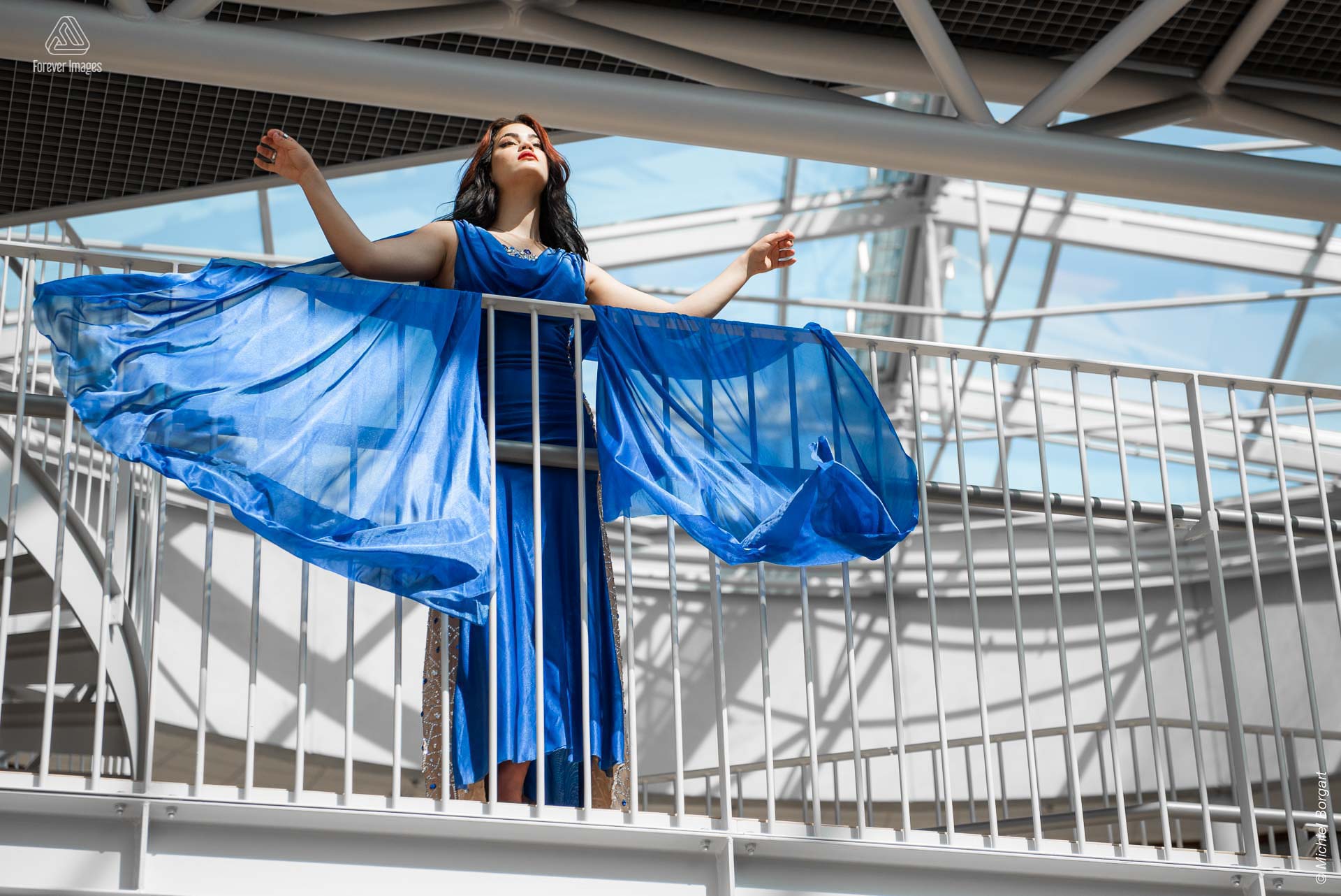 Fashion photo glamor beautiful lady blue dress hanging over railing | Daphna Akkermans David Cardenas | Fashion Photographer Michiel Borgart - Forever Images.
