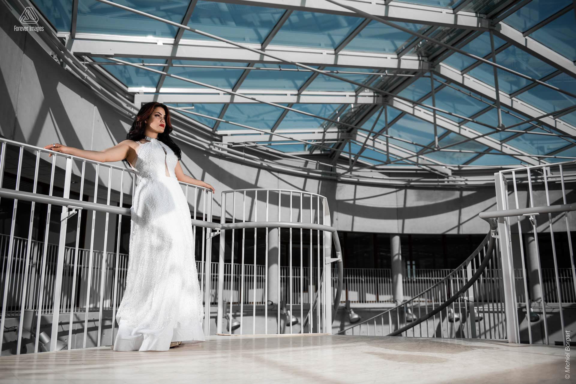 Fashionfoto glamour mooie dame onder glazen plafond witte jurk | Daphna Akkermans David Cardenas | Fashionfotograaf Michiel Borgart - Forever Images.