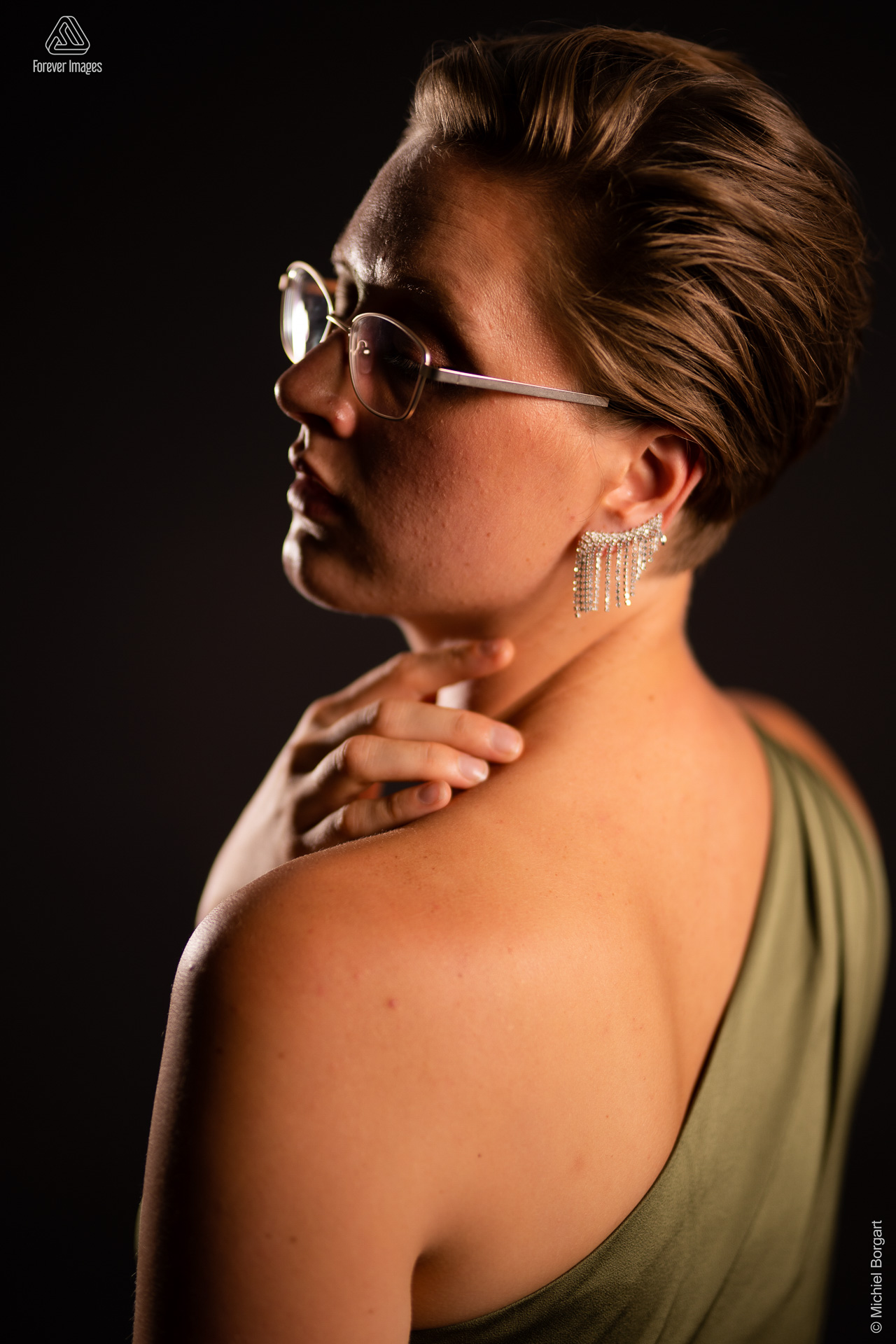 Portrait photo young lady beautiful green dress with open back glasses earrings hand in neck | Carmen | Portrait Photographer Michiel Borgart - Forever Images.