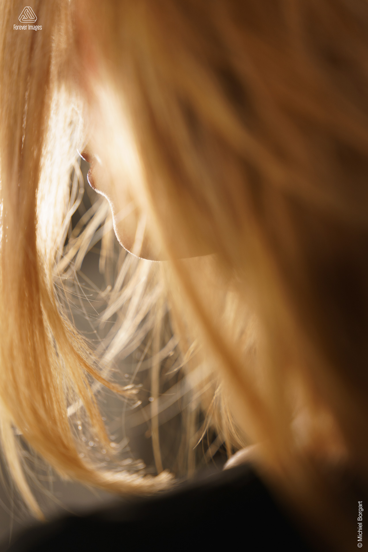 Portretfoto jonge dame close-up verscholen in blonde haren | Fanziska | Portretfotograaf Michiel Borgart - Forever Images.