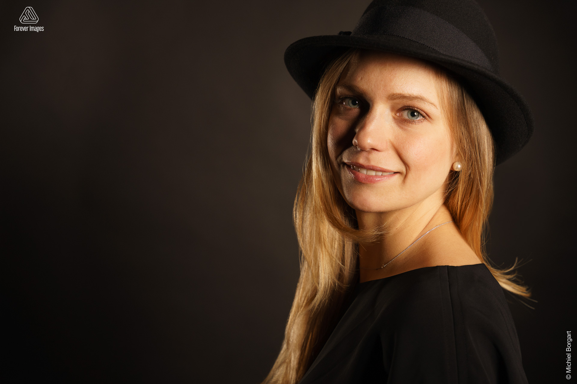 Portretfoto jonge dame blond haar zwart jurkje met zwarte hoed | Fanziska | Portretfotograaf Michiel Borgart - Forever Images.