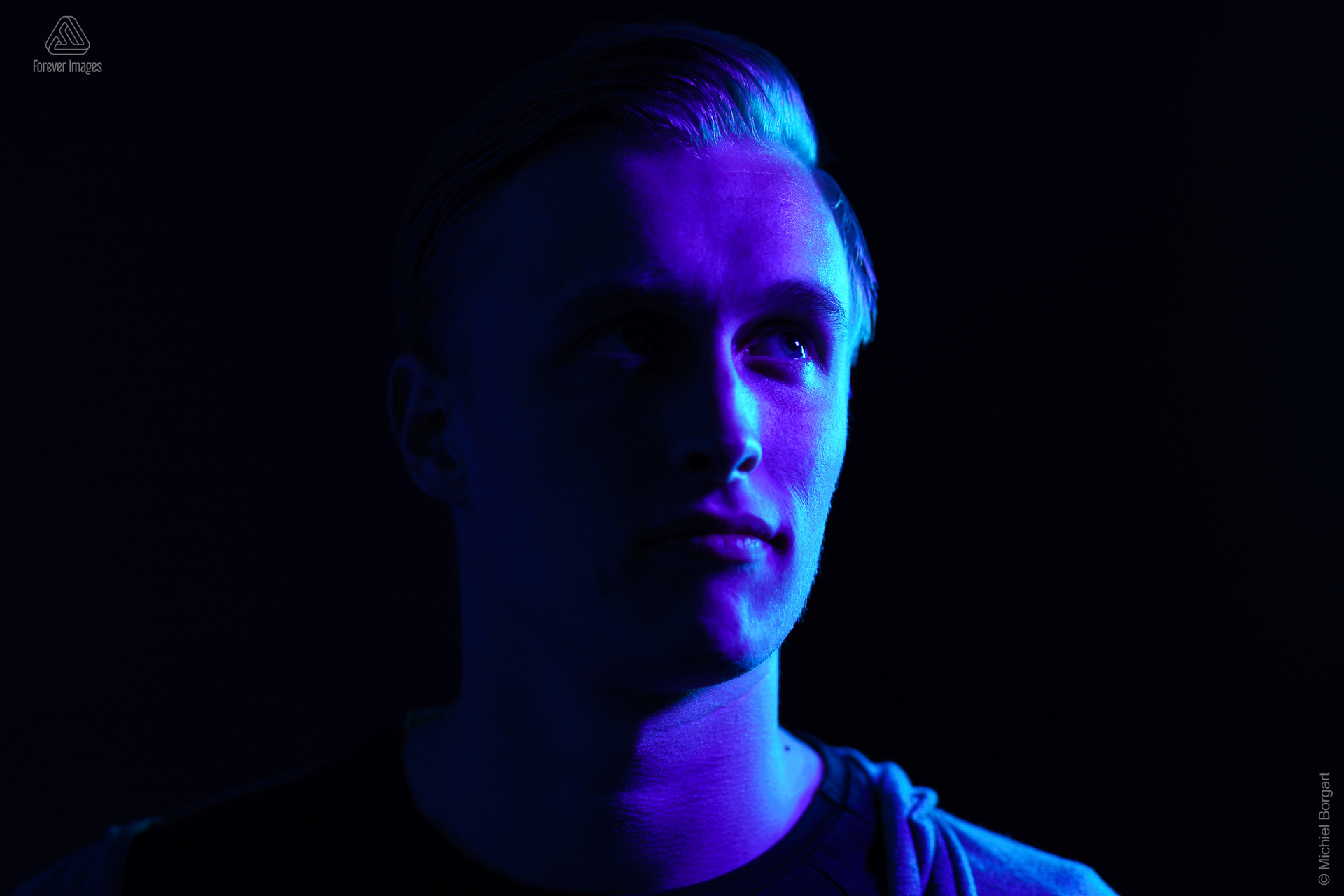 Portrait photo low key young man in studio with blue and purple light | Alex | Portrait Photographer Michiel Borgart - Forever Images.