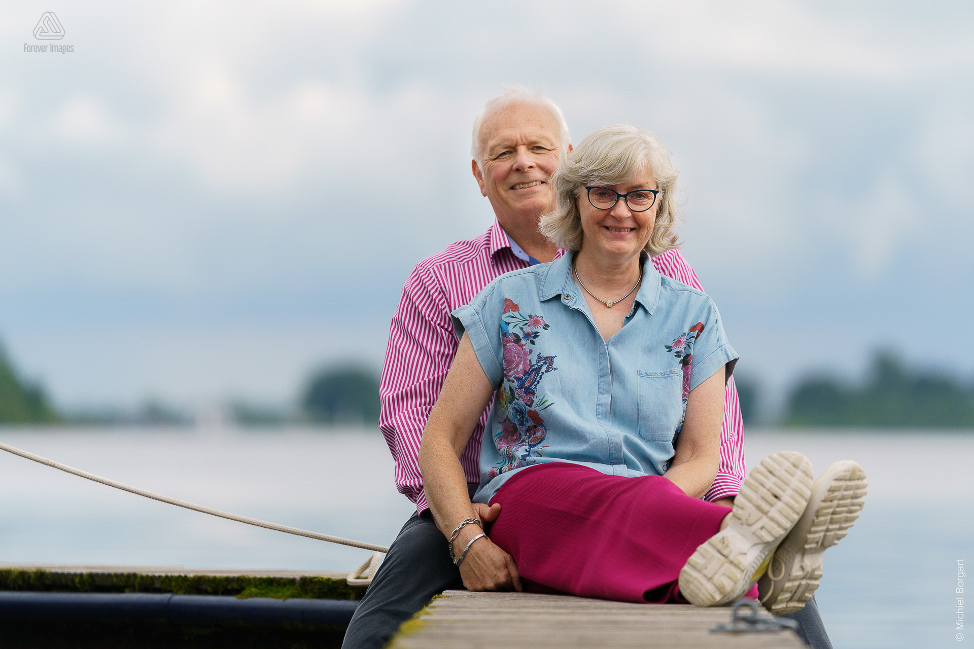 Portrait photo couple sitting together on pier Loosdrecht | Ronald Marja Mensa HiQ Magazine | Portrait Photographer Michiel Borgart - Forever Images.