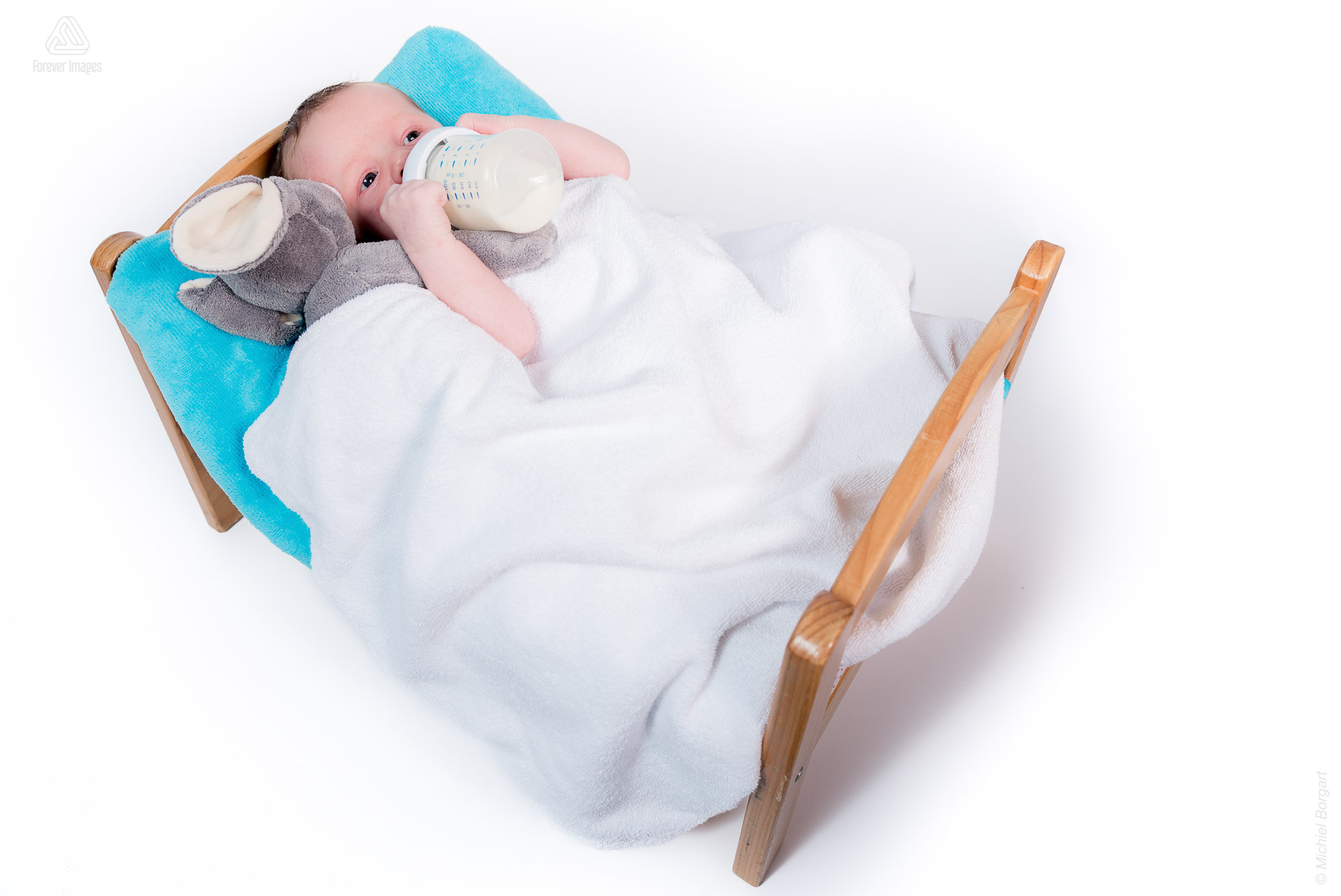 Portretfoto pasgeboren baby new born in zijn bedje aan de fles | Kylian | Portretfotograaf Michiel Borgart - Forever Images.