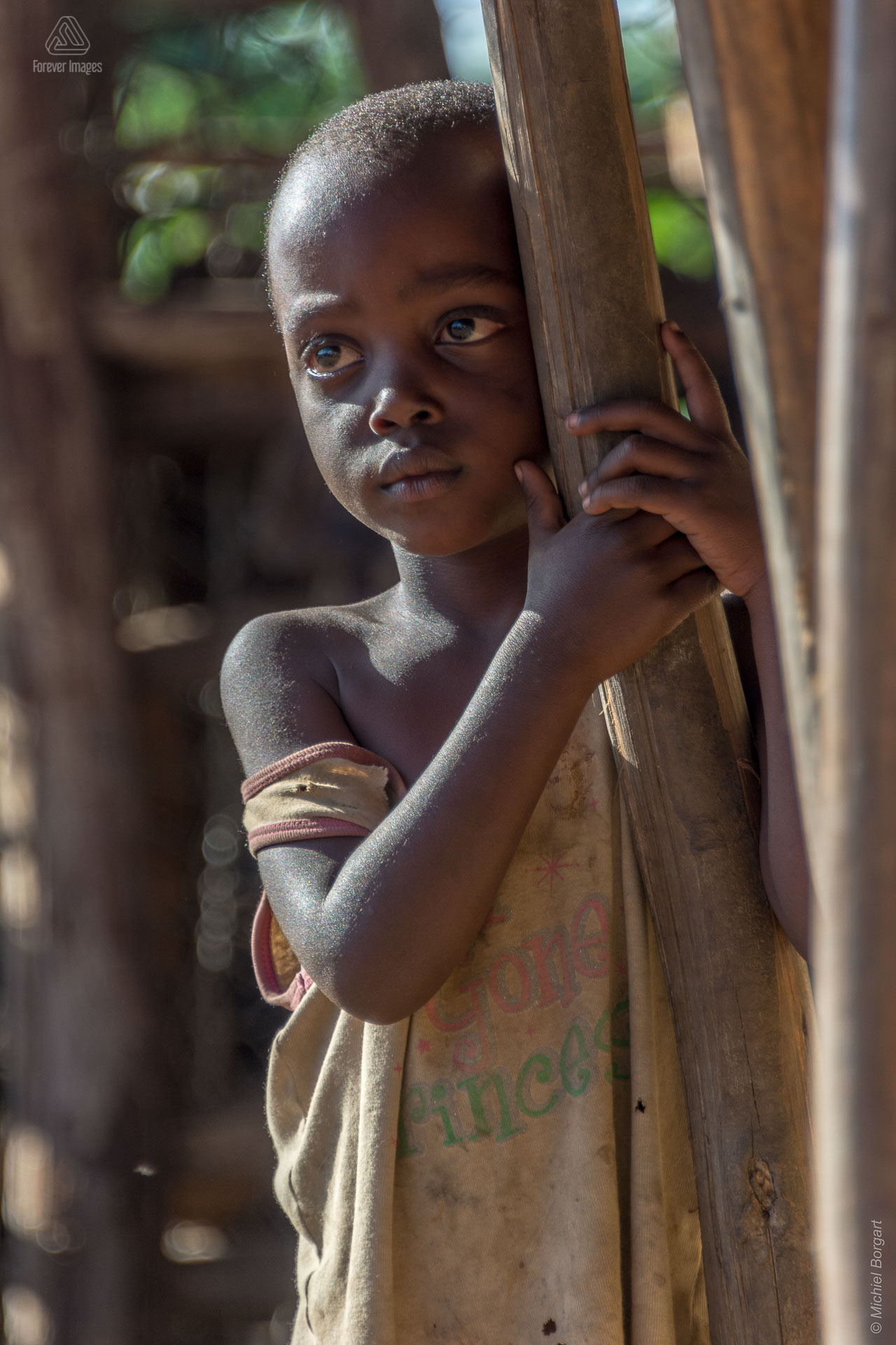 Portretfoto kindje houd hek vast Oeganda tijdens de Muskathlon van 2015 | Portretfotograaf Michiel Borgart - Forever Images.
