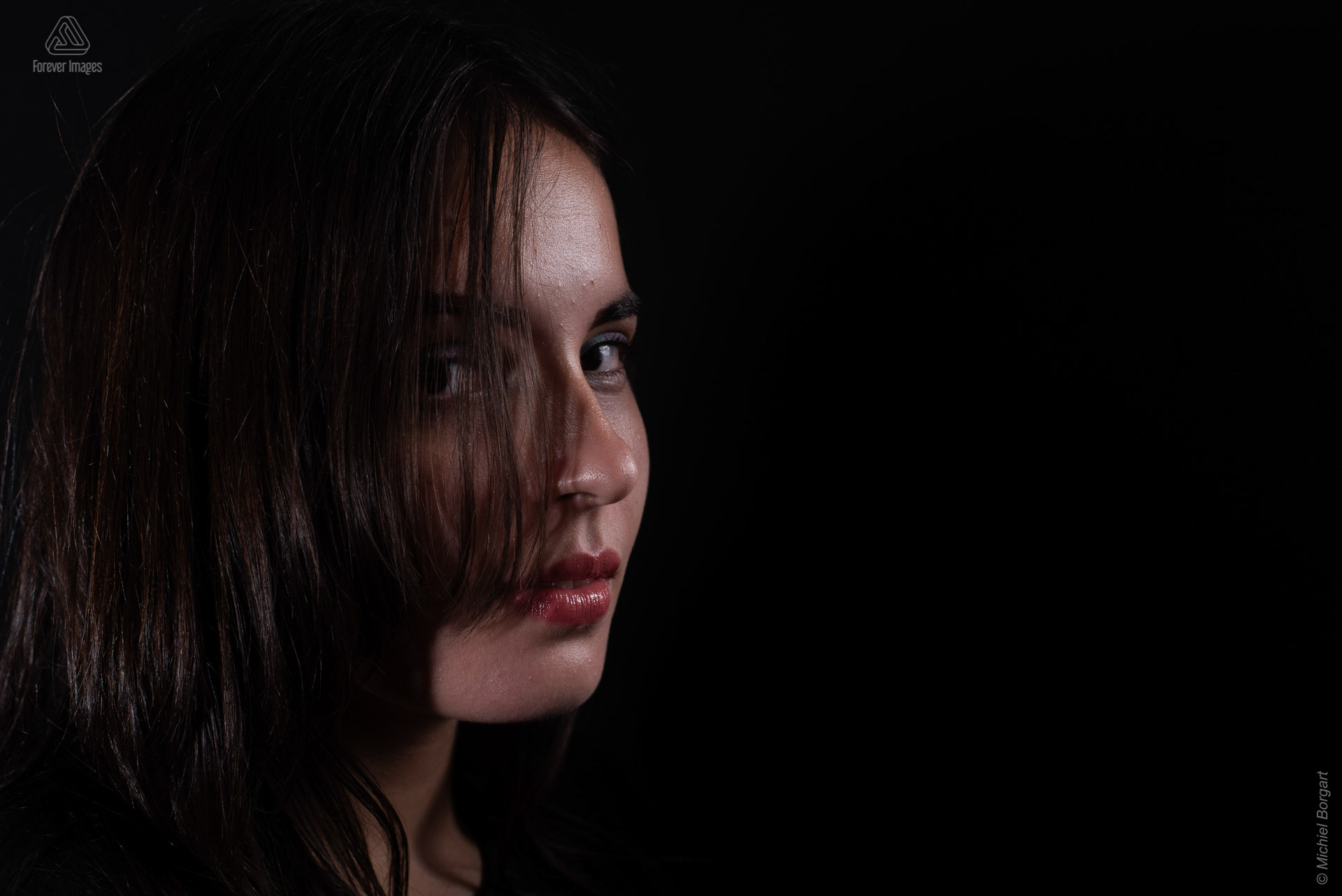 Portretfoto jonge dame kijkt door haar low key | Isis Vaandrager | Portretfotograaf Michiel Borgart - Forever Images.