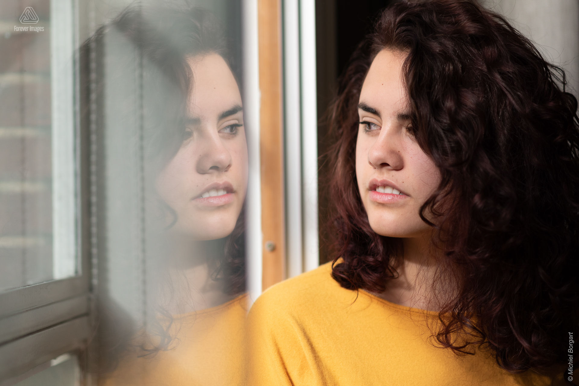 Portretfoto jonge dame kijkt uit raam met reflectie in raam | Tessa Holscher | Portretfotograaf Michiel Borgart - Forever Images.