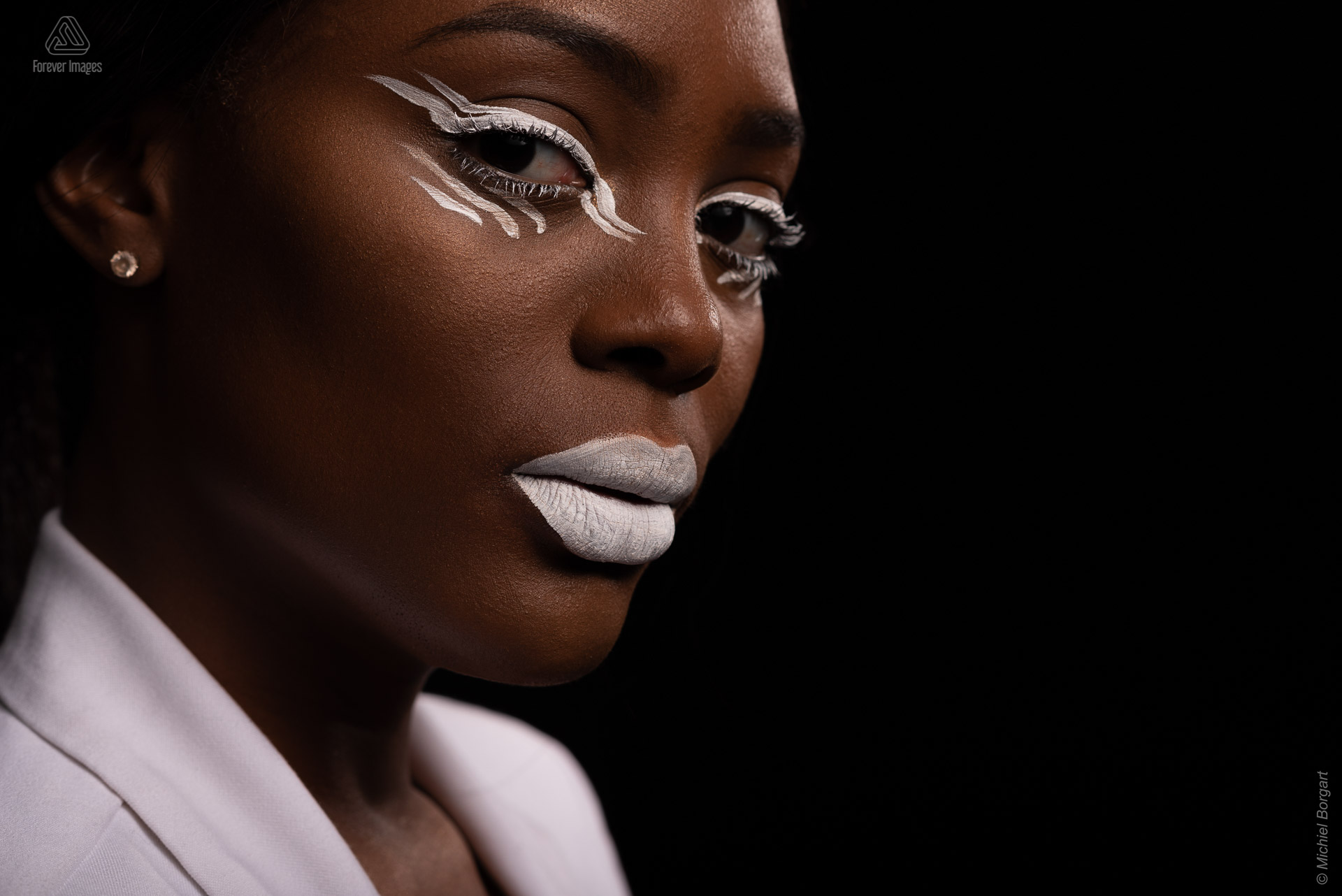 Portretfoto glamourshoot witte make-up kijkend in camera | Mariana Pietersz Natasha Mondesir | Portretfotograaf Michiel Borgart - Forever Images.