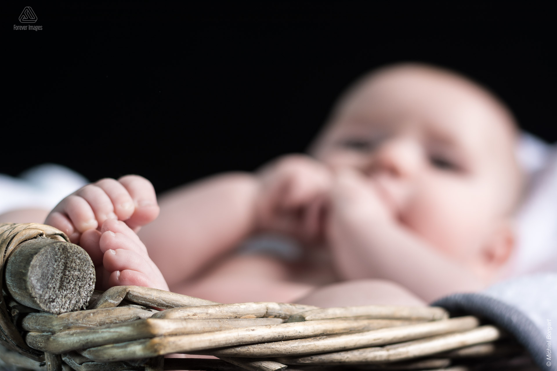 Kinderfoto baby in riete mandje waarbij de focus op zijn teentjes ligt | Elias | Portretfotograaf Michiel Borgart - Forever Images.