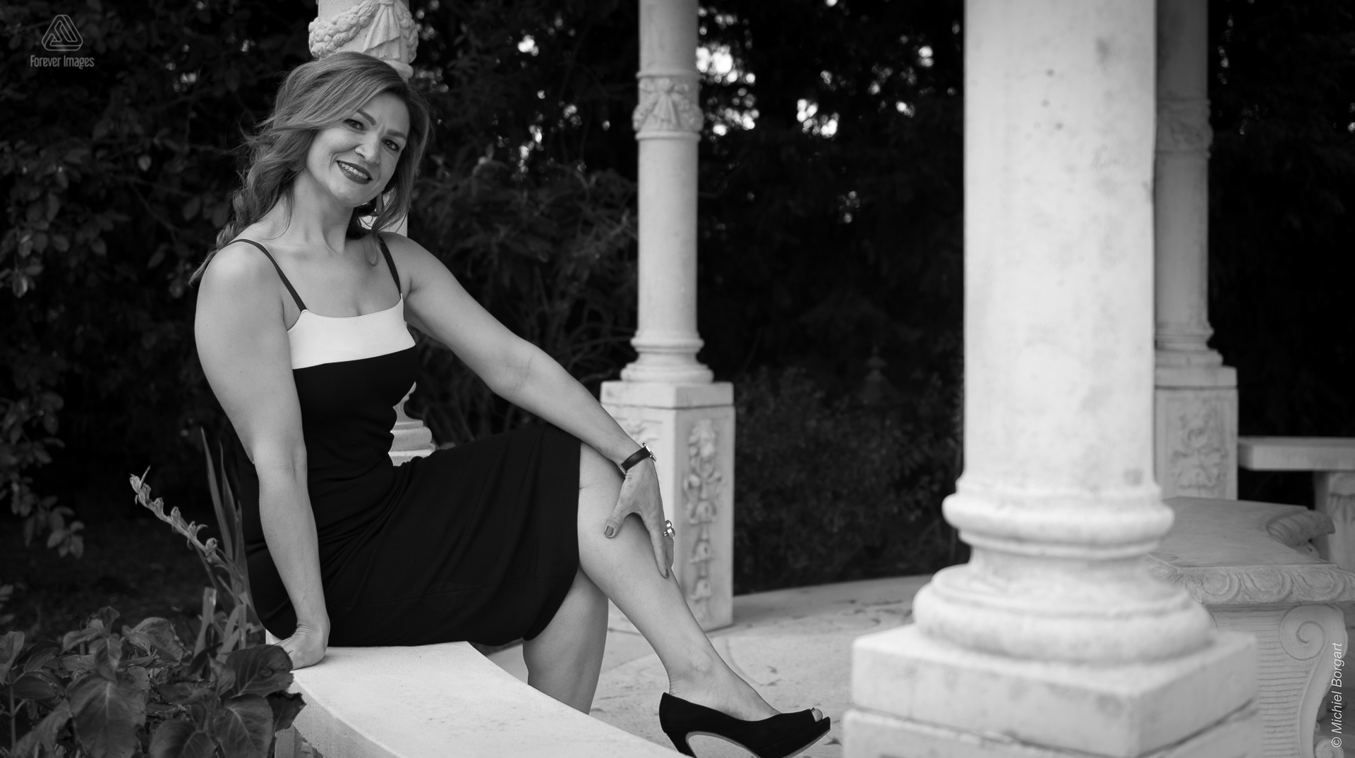 Portretfoto in zwart-wit mooie dame die zit in prieel met witte pilaren | Portretfotograaf Michiel Borgart - Forever Images.
