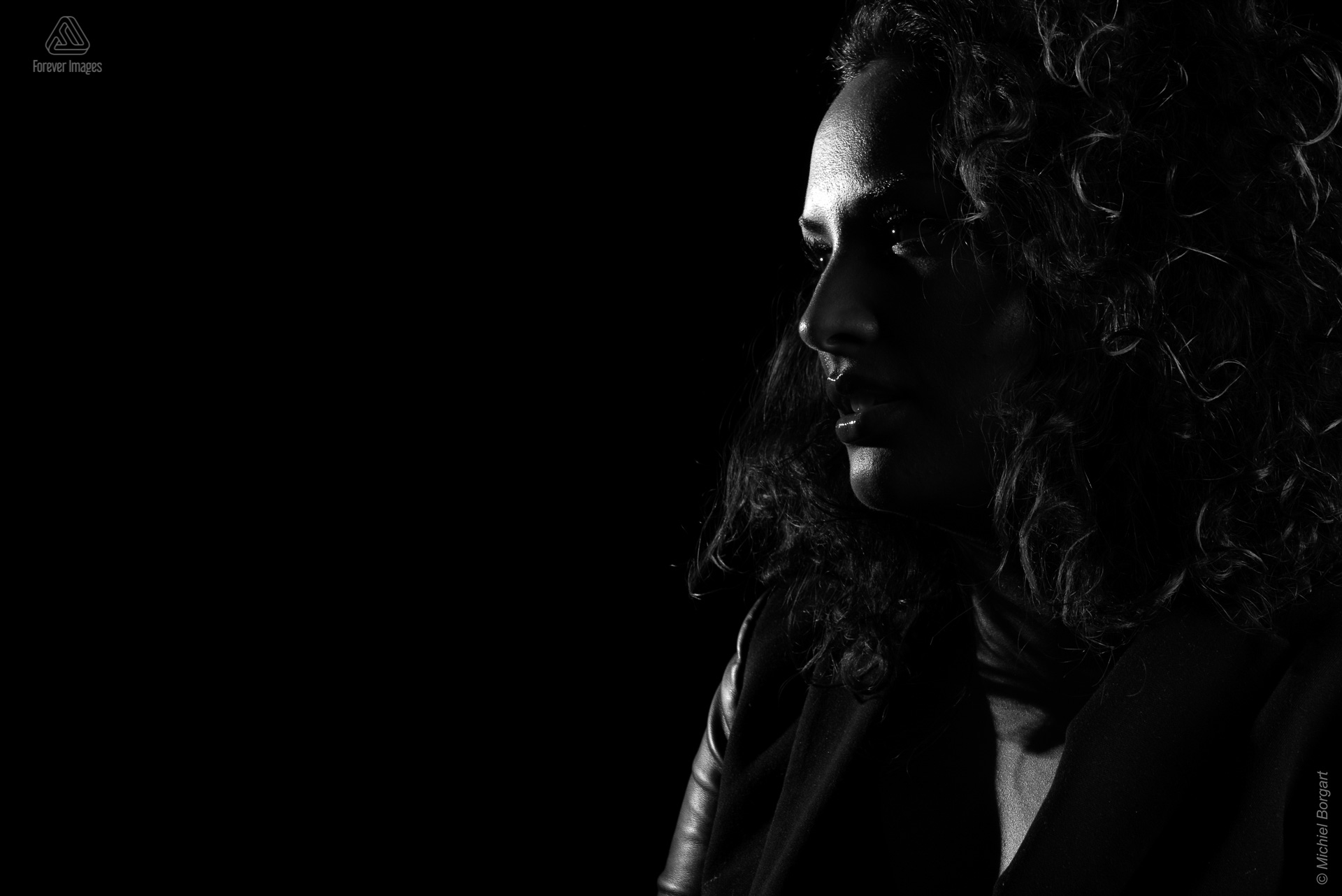 Portretfoto zwart-wit low key film noir studio mooie jonge dame kijkend naar opzij | Jessica | Portretfotograaf Michiel Borgart - Forever Images.