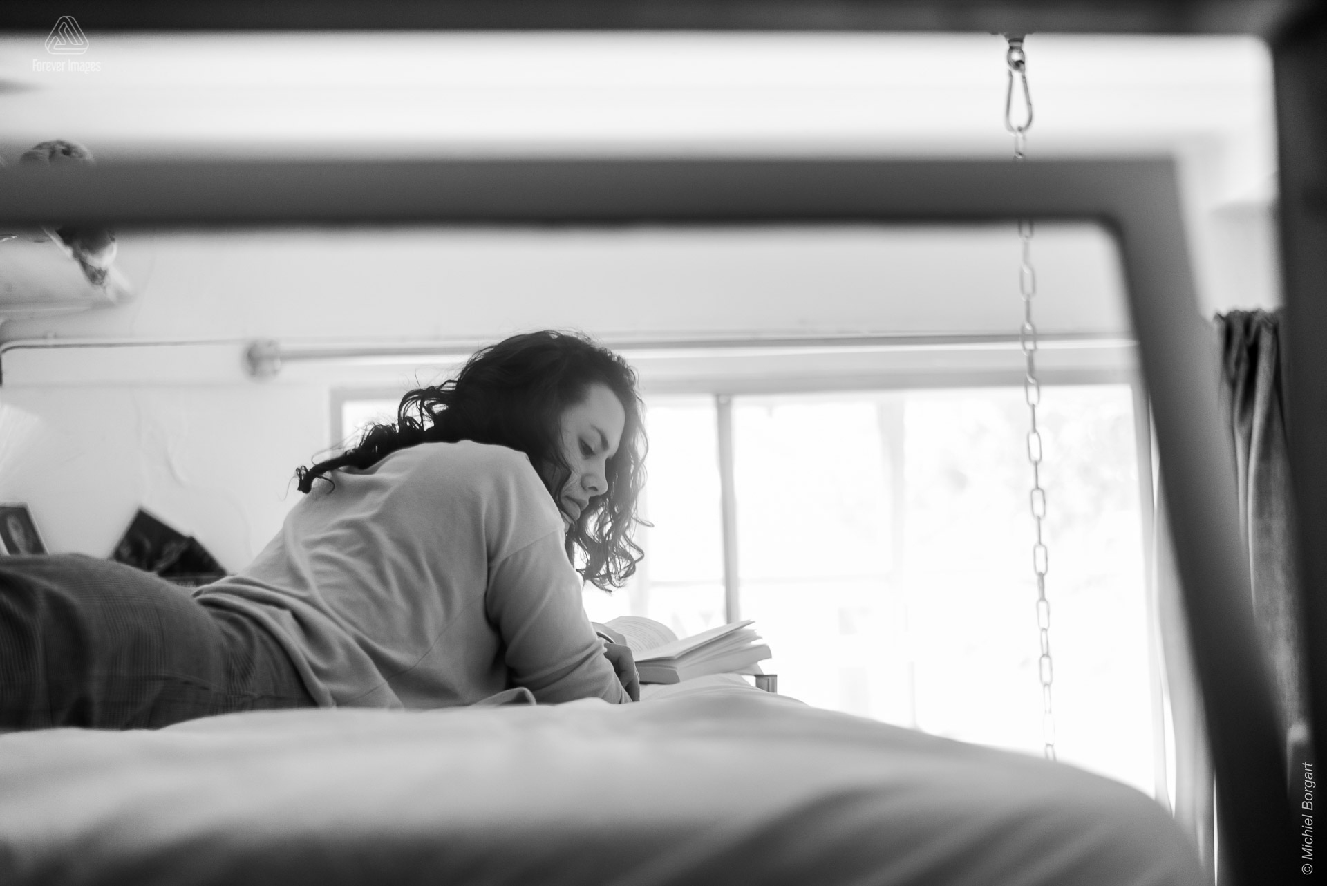 Portretfoto zwart-wit jonge dame kijkt opzij op bed door raam | Tessa Holscher | Portretfotograaf Michiel Borgart - Forever Images.
