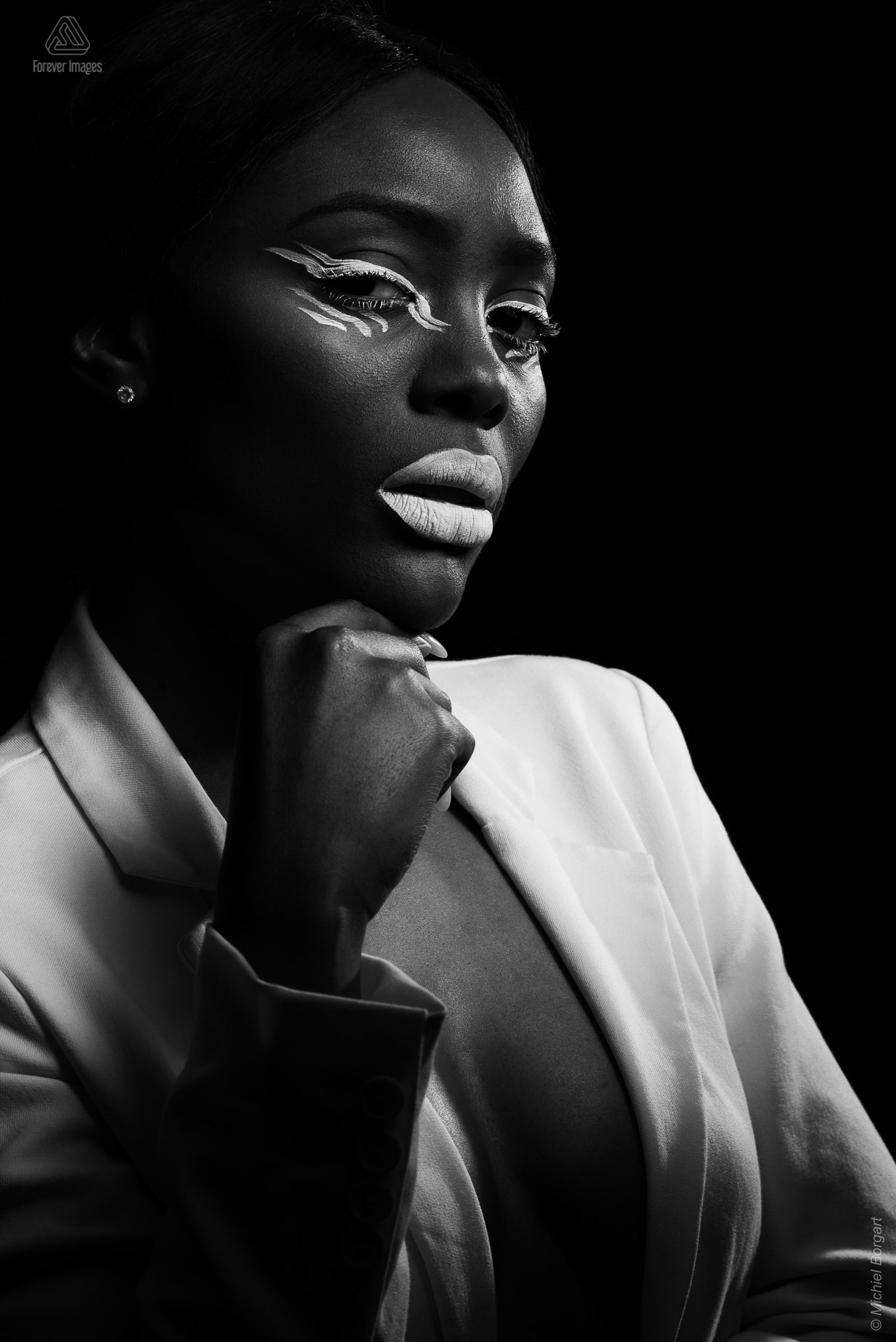 Portretfoto zwart-wit glamourshoot witte make-up wit jasje low key | Mariana Pietersz Natasha Mondesir | Portretfotograaf Michiel Borgart - Forever Images.
