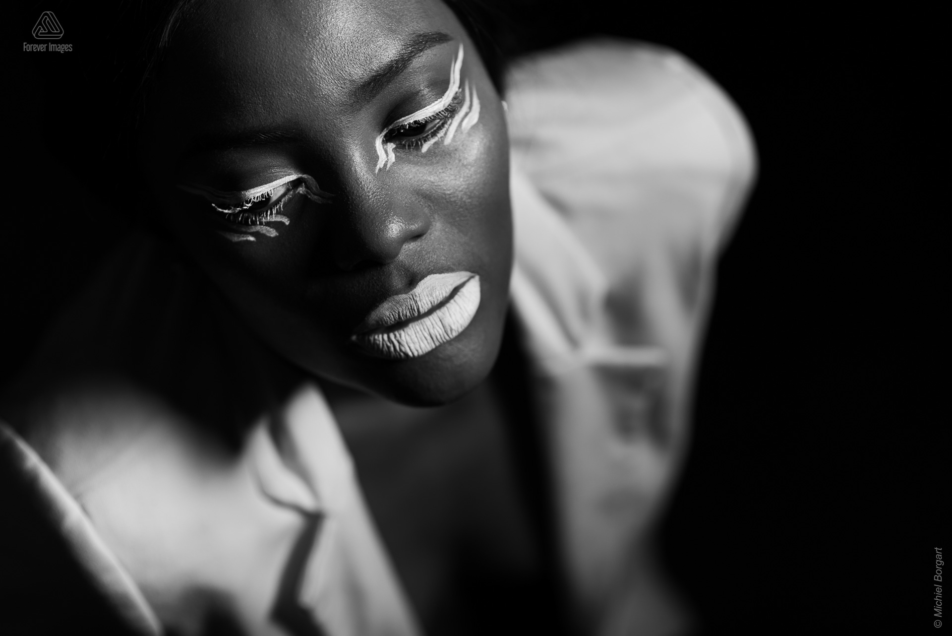 Portretfoto zwart-wit glamour witte make-up wit jasje boven low key | Mariana Pietersz Natasha Mondesir | Portretfotograaf Michiel Borgart - Forever Images.