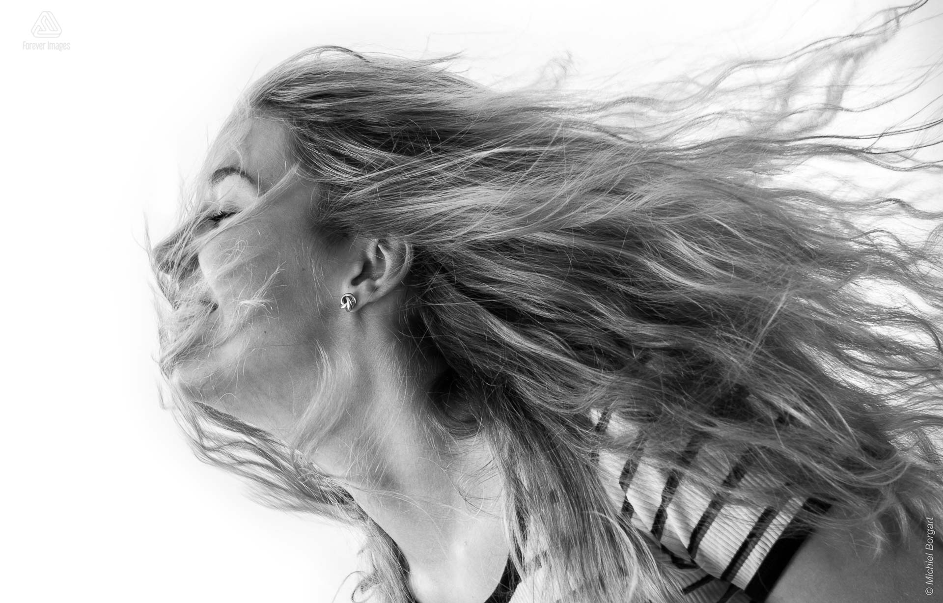 Portretfoto in zwart-wit jonge blonde dame met het haar los en in haar gezicht | Nicolette | Portretfotograaf Michiel Borgart - Forever Images.