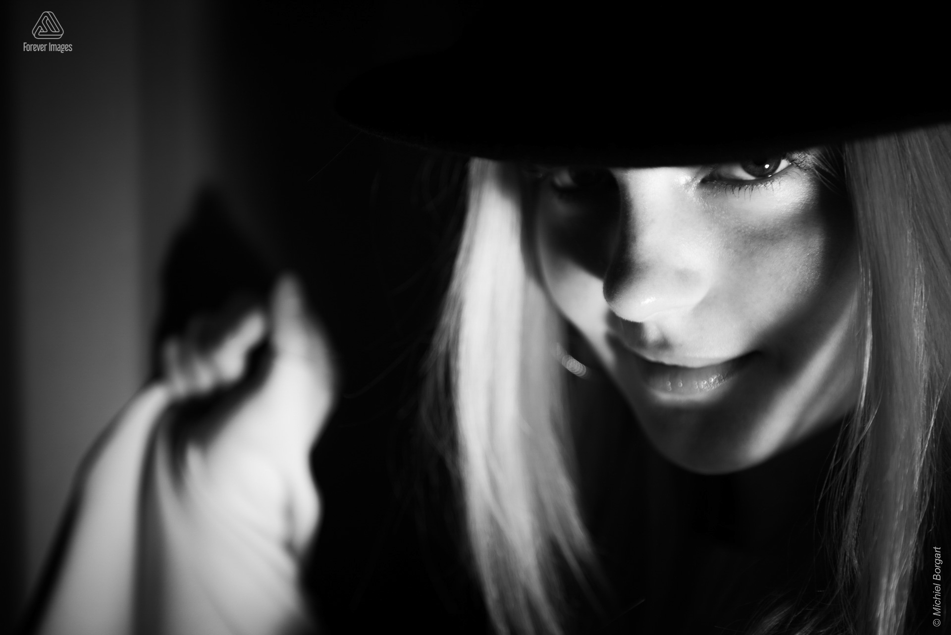 Portretfoto zwart-wit low key jonge dame zwarte hoed scherpe blik | Porscha Luna de Jong Happyhappyjoyjoy | Portretfotograaf Michiel Borgart - Forever Images.