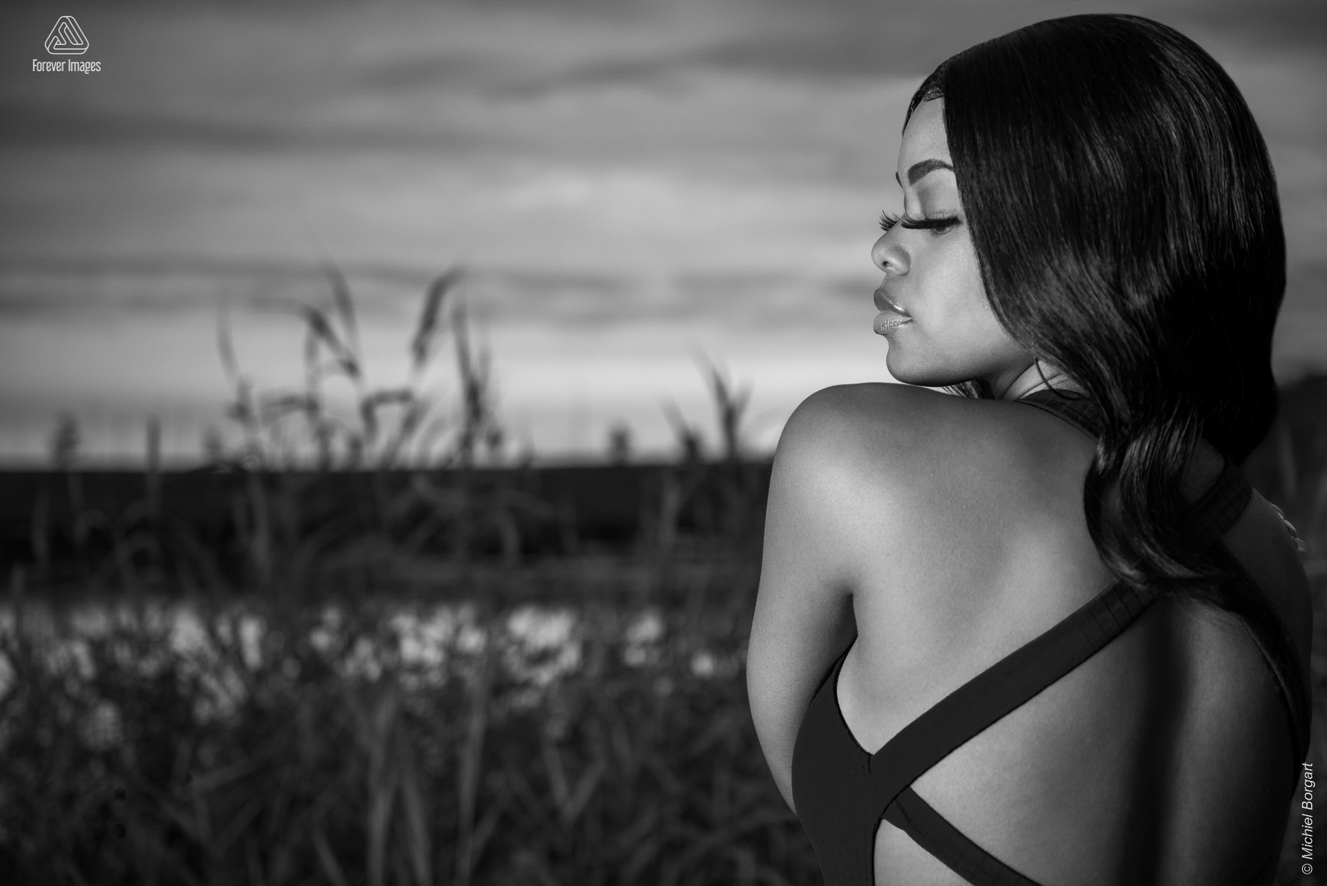 Portrait photo black and white B&W young lady dress open back grass and water | Mariangel Dolorita Diemer Polder | Portrait Photographer Michiel Borgart - Forever Images.