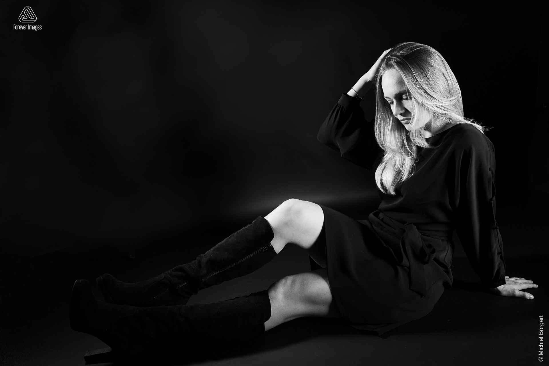 Portretfoto zwart-wit low key jonge dame zittend zwart jurkje en zwarte laarzen | Fanziska | Portretfotograaf Michiel Borgart - Forever Images.