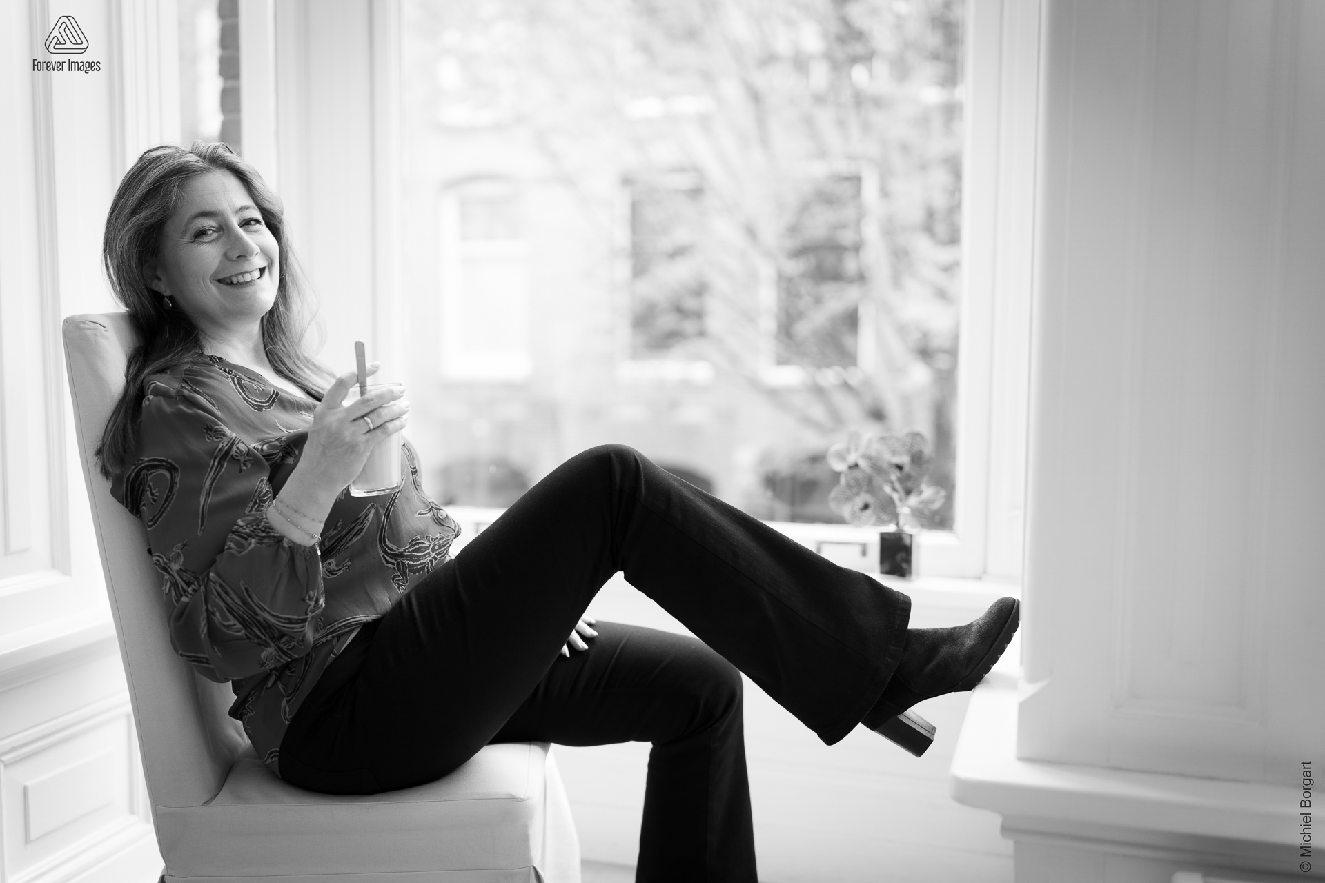 Portretfoto zwart-wit dame zit met koffie bij het raam | Mirjam Bach Kleurkeuze | Portretfotograaf Michiel Borgart - Forever Images.