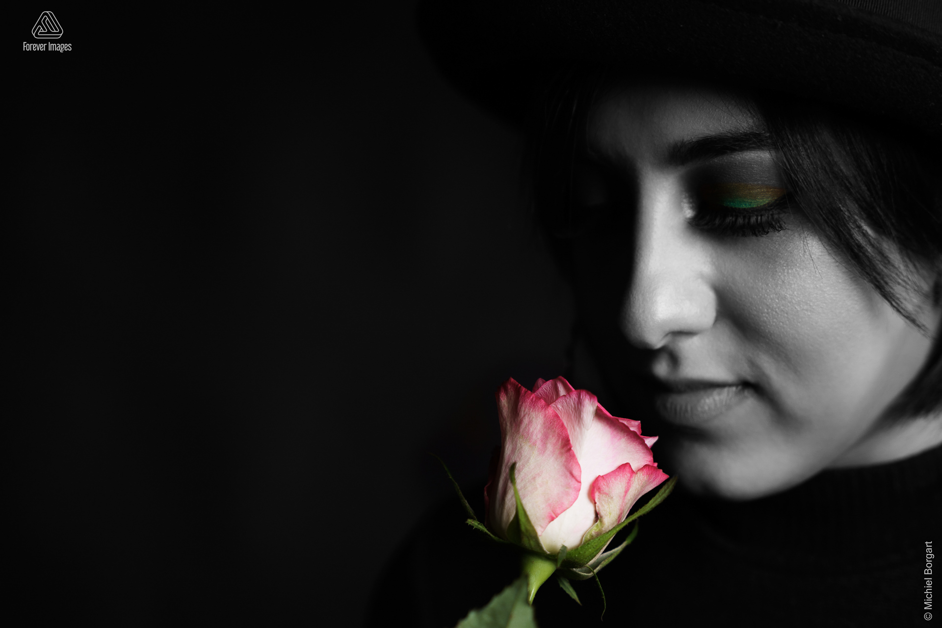 Portretfoto zwart-wit low key selective color jonge dame ruikt aan een roos | Arfa | Portretfotograaf Michiel Borgart - Forever Images.