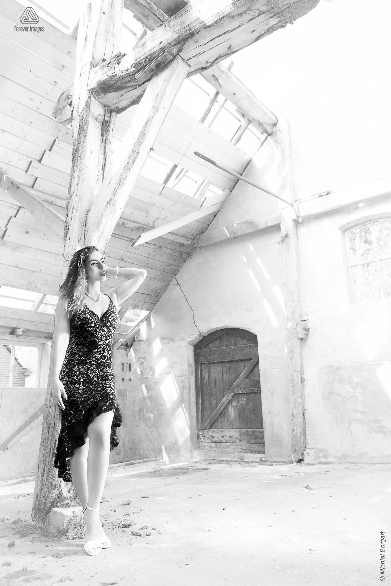 Portretfoto urbex zwart-wit mooie dame in vervallen schuur tegen houten pilaar | Floriana Horta | Portretfotograaf Michiel Borgart - Forever Images.