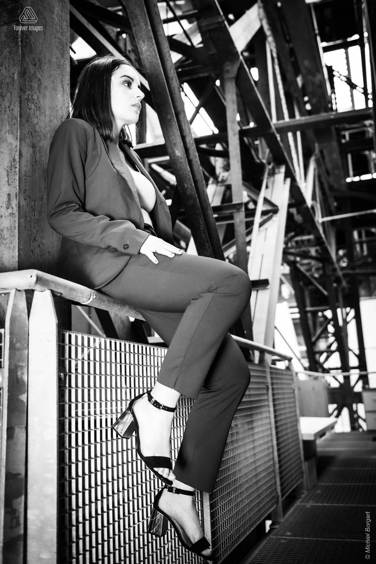 Portrait photo black and white B&W lady sitting on railing | Isis Vaandrager NDSM Werf Amsterdam | Portrait Photographer Michiel Borgart - Forever Images.